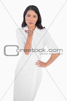 Elegant dark haired model wearing white dress kissing camera