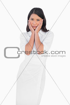 Elegant dark haired model wearing white dress touching her face