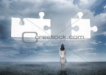 Businesswoman standing looking at jigsaw puzzle