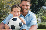 Happy dad and son with a football in a park