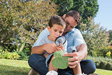 Cheerful dad and son inspecting leaf with a magnifying glass