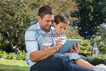 Dad and son using a tablet pc in a park