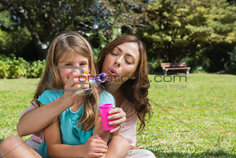 Smiling daughter with mother making bubbles