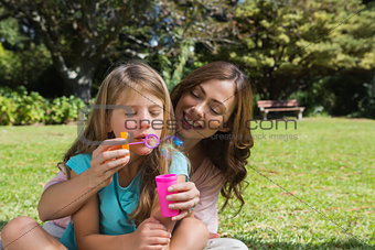 Daughter blowing bubbles with mother