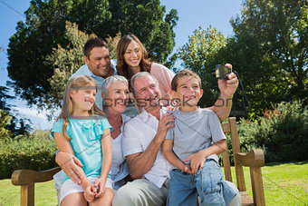Family sitting on a bench taking photo of themselves