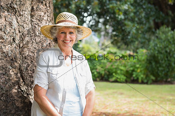 Cheerful retired woman sitting on tree trunk