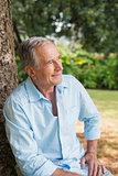 Thoughtful retired man sitting on tree trunk