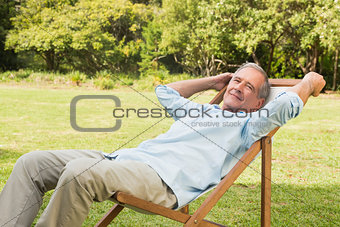 Happy mature man sitting on sun lounger