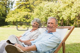Happy mature couple sitting on sun loungers