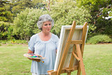 Happy mature woman painting on canvas