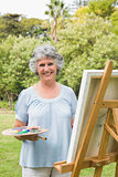 Smiling mature woman painting on canvas