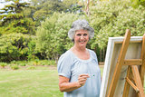 Smiling retired woman painting on canvas