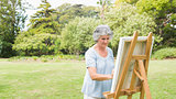 Peaceful retired woman painting on canvas