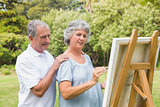 Peaceful retired woman painting on canvas with husband