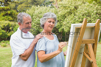 Peaceful retired woman painting on canvas with husband