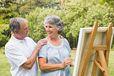 Happy retired woman painting on canvas with husband