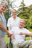 Happy man in a wheelchair with his nurse and wife