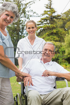 Happy man in a wheelchair with his nurse and wife