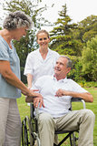 Happy man in a wheelchair talking with his nurse and wife