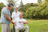 Happy man in a wheelchair laughing with his nurse and wife