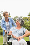 Cheerful mature woman in wheelchair talking with daughter