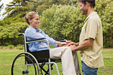 Attractive woman in wheelchair with partner kneeling beside her