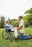 Blonde woman in wheelchair with partner kneeling beside her