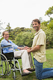 Blonde woman smiling in wheelchair with partner kneeling beside her