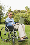 Smiling young woman in a wheelchair with a laptop