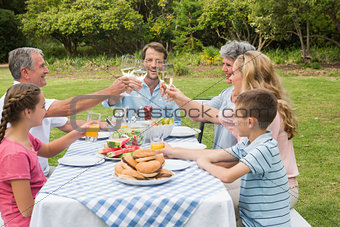 Multi generation family toasting each other at dinner outside