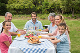 Multi generation family having dinner outside at picnic table