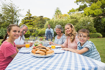 Smiling extended family waiting for barbecue being cooked by father