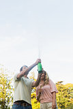 Man spraying bottle of champagne with blonde partner