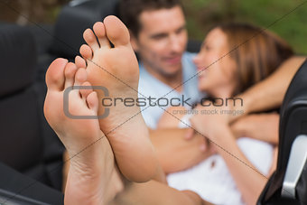 Cute couple cuddling in the backseat with focus on foot