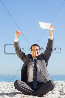 Victorious young businessman holding up his tablet computer