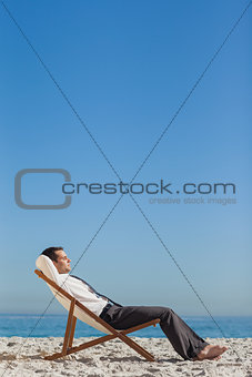 Young businessman relaxing and tanning on his deck chair