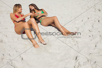 Smiling tanned blonde and brunette having beers