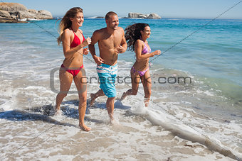 Cheerful friends jogging on the beach