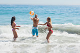 Cheerful friends playing with a beachball in the sea