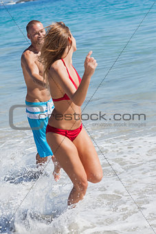 Cheerful couple in swimsuit bathing together
