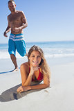 Smiling woman lying on the sand while man joining her
