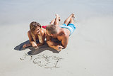 Loving couple drawing in the sand