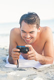 Smiling handsome man lying on his towel looking at his camera