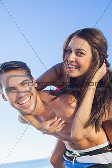Cheerful handsome man carrying his girlfriend on his back