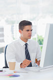 Young businessman frowning while looking at computer