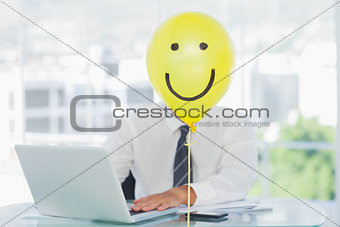 Yellow balloon with happy face hiding businessmans face