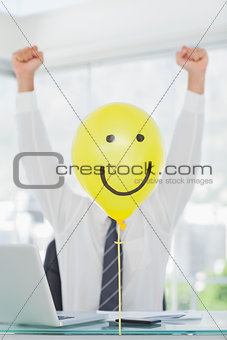 Yellow balloon with happy face hiding cheerful businessmans face