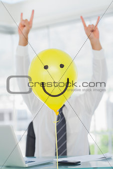Yellow balloon with cheerful face hiding rock and roll businessman