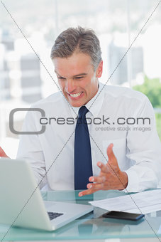 Angry businessman looking at his laptop