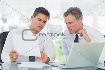 Concentrated businessman listening to his intern while explaining documents